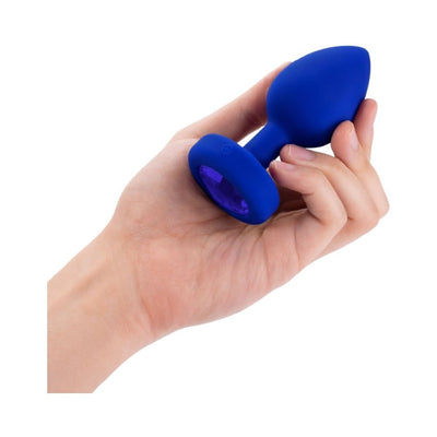 Hand holding a blue silicone vibrating jewel plug with a faceted sapphire-colored base jewel.