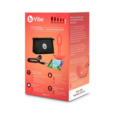 Packaging of b-Vibe Vibrating Snug Plug in small orange with USB charger, storage pouch, and user guide on a gradient orange background.