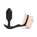 Black silicone b-Vibe Vibrating Snug & Tug Medium with penis ring and weighted plug shown on anatomical model.
