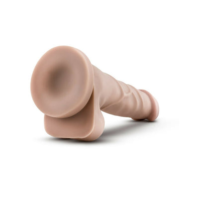 Beige realistic dildo with suction cup base lying on white background, textured for lifelike feel.