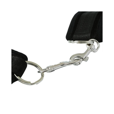 Close-up of black beginner's handcuffs with soft Velboa material and metal snap link connector on white background.