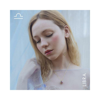 Woman with closed eyes wearing a delicate Rhodochrosite gemstone necklace from the Libra Horoscope Kit by Bijoux Indiscrets.