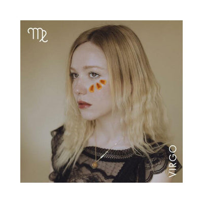 Portrait of a woman with blonde hair wearing a black lace top and a citrine necklace, Virgo zodiac symbol and name displayed.