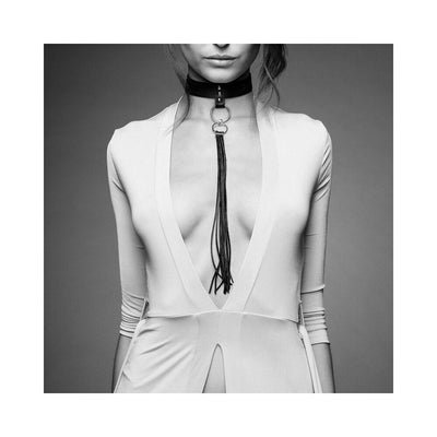 Black vegan leather tassel choker with metal rings worn over a deep V-neck white dress on a model.
