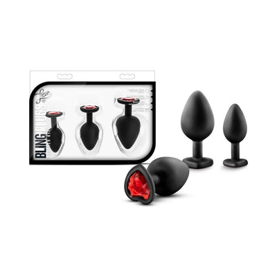 Set of three black silicone plugs in small, medium, and large sizes with heart-shaped bases featuring red gems, displayed with packaging.