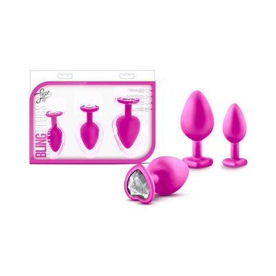 Three pink silicone tapered plugs in small, medium, and large sizes with heart-shaped bases and white gem accents, displayed with packaging.