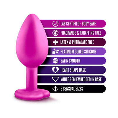 Pink silicone plug with heart-shaped base and white gem, highlighting body-safe, fragrance-free, latex-free, and satin-smooth features.