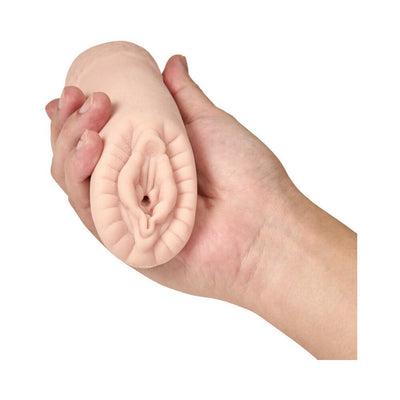 Hand holding a compact, natural-colored male pleasure sleeve with textured, ribbed opening.