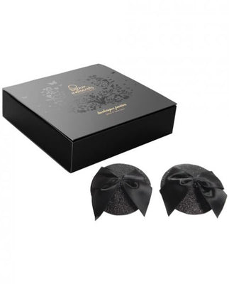 Black glitter burlesque pasties with satin bows next to a sleek black decorative box packaging.