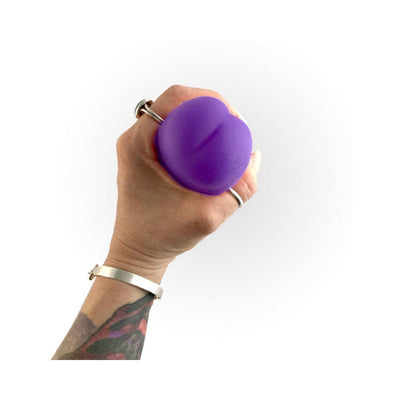 Hand holding the thick purple silicone pleasure toy with a strong suction cup base against a white background.