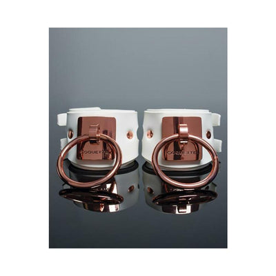 White vegan leather cuffs with rose gold metal rings and engraved Coquette plates, adjustable buckle closures.