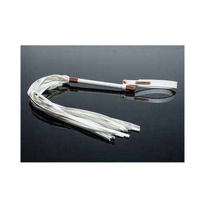 White vegan leather whip with multiple tails, a sleek handle, and an adjustable wrist strap with metal accents on a reflective black surface.