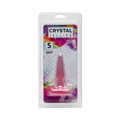 Small pink Crystal Jellies butt plug in clear retail packaging with colorful geometric background.