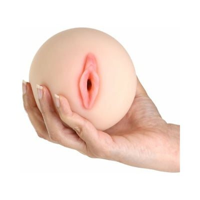 Hand holding a compact, lifelike textured stroker with realistic vaginal opening in soft skin tone.