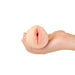 Hand holding a compact lifelike stroker with soft skin tone and detailed vaginal opening.