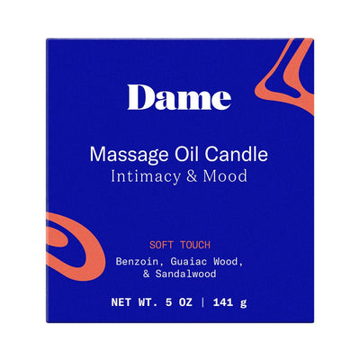 Dame Massage Oil Candle box in blue with orange accents, featuring soft touch scent with benzoin, guaiac wood, and sandalwood.