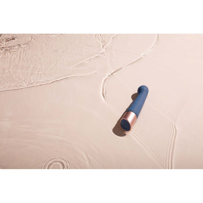 Blue and rose gold silicone wellness device resting on soft rippling water surface.
