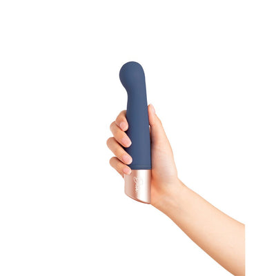 Hand holding a sleek blue silicone personal massager with a curved tip and rose gold base.
