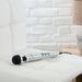 Compact silver Doxy Die Cast 3 wand vibrator with black silicone head resting on a white cushioned chair.