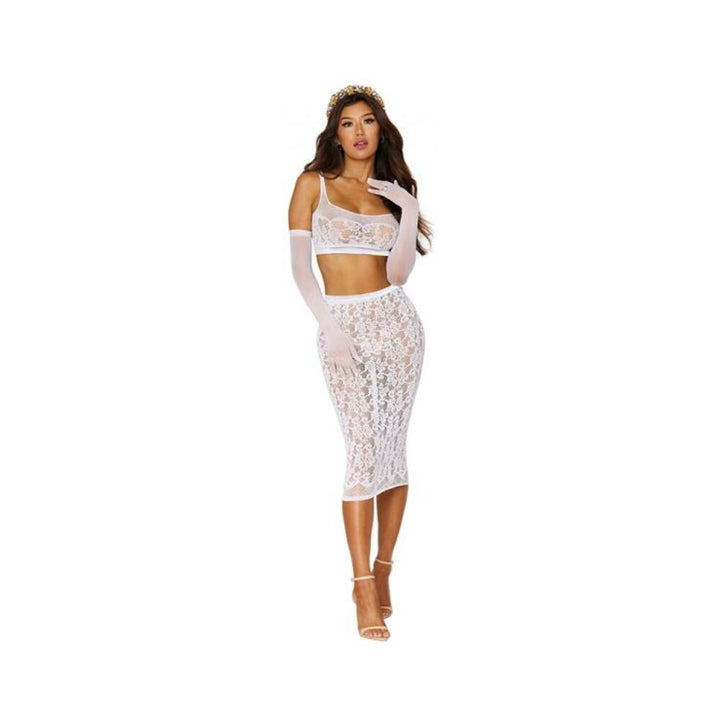 Model wearing a white sheer lace bralette and matching slip skirt with floral pattern and long white gloves.