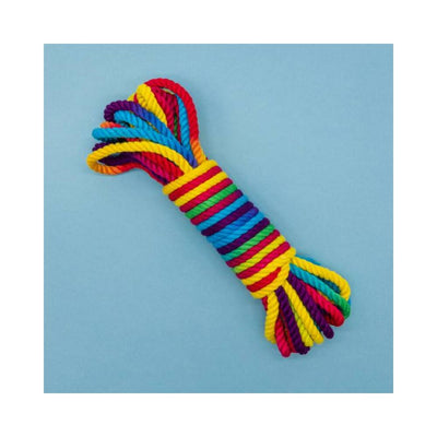 Coiled rainbow-colored bamboo silk bondage rope with vibrant stripes on a light blue background.