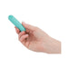 Hand holding a compact teal rechargeable vibrating bullet with a smooth matte finish and power button on top.