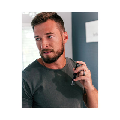 Man with beard applying Eye of Love Matchmaker Pheromone Perfume Black Diamond spray on neck indoors