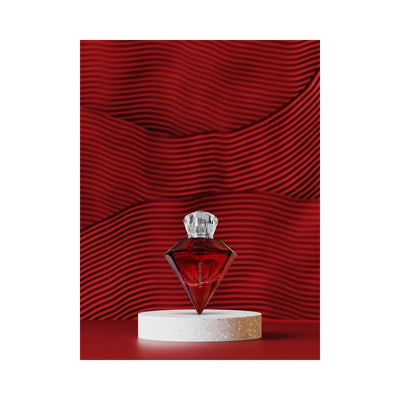 Red diamond-shaped Eye of Love Matchmaker pheromone parfum bottle on white pedestal with textured red background