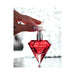 Hand holding red diamond-shaped perfume bottle with silver spray nozzle against a sparkling background