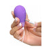 Hand holding a purple silicone remote-controlled kegel exerciser with a white charging cable being plugged in.