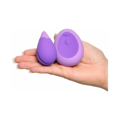 Hand holding a compact purple silicone remote-controlled Kegel exerciser and matching oval remote.