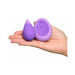 Hand holding a compact purple silicone remote-controlled Kegel exerciser and matching oval remote.