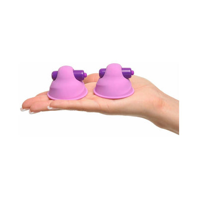 Hand holding two small pink and purple silicone vibrating nipple stimulators with compact design.