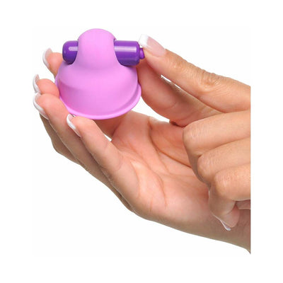Hand holding a small pink silicone vibrating nipple stimulator with purple vibration bar on top.