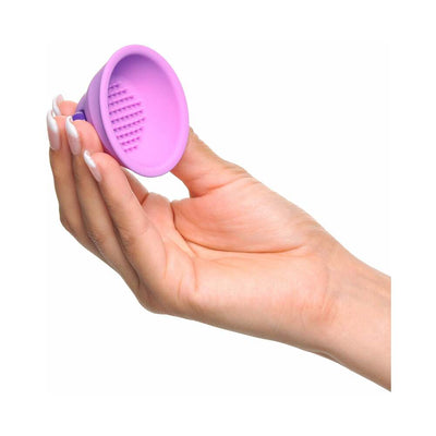 Hand holding a small purple silicone vibrating nipple stimulator with textured interior nubs.