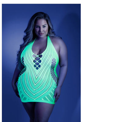 Plus size model wearing neon green glow net halter dress with open back and intricate cutout patterns under blue lighting.
