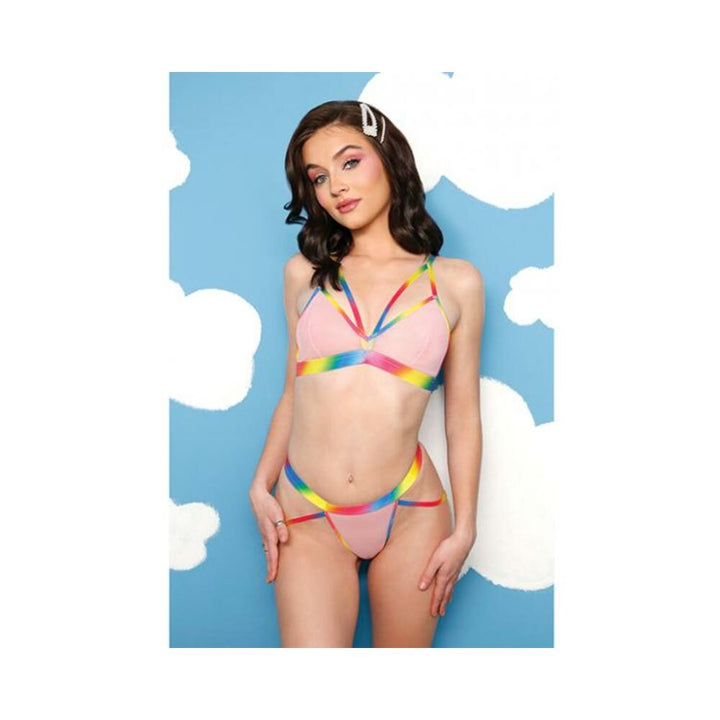 Model wearing Fantasy Lingerie Vibes rainbow caged bralette and panty set with booty harness against blue cloud background.