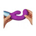 Hands holding a purple dual-density liquid silicone rabbit vibrator with textured curved design and silver handle.