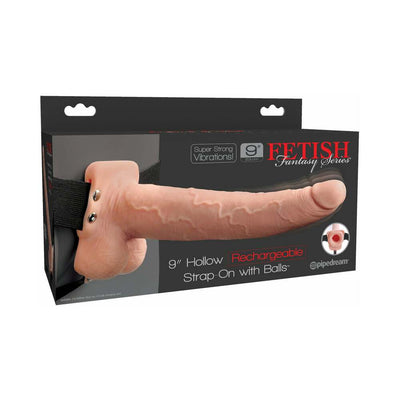 Flesh-colored 9-inch hollow rechargeable strap-on with balls in adjustable black harness, displayed in product packaging.