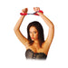 Woman wearing black corset with red furry handcuffs raised above her head on white background