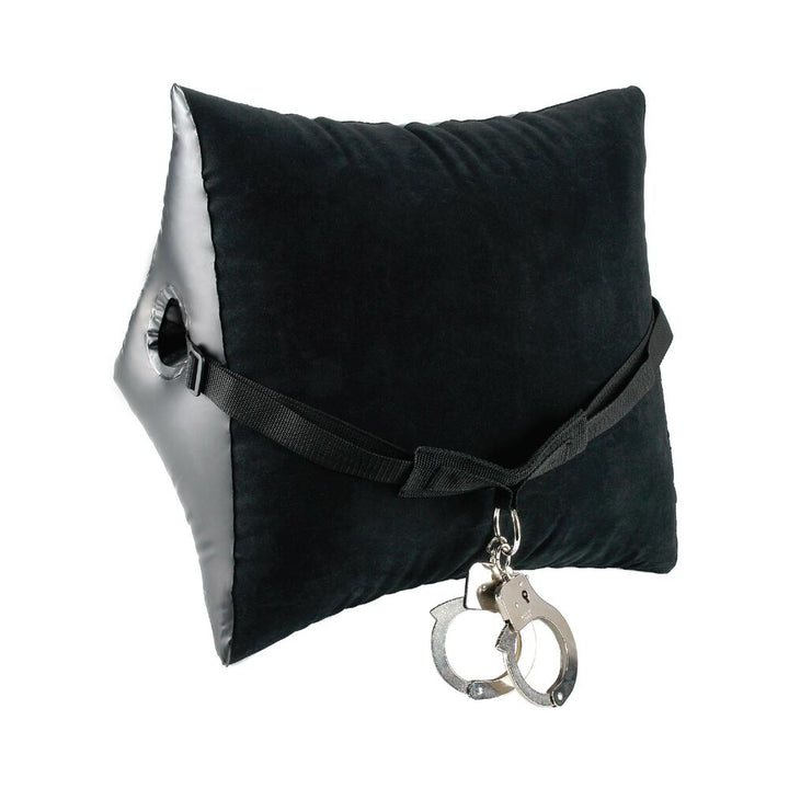 Inflatable wedge pillow with black velvety surface, adjustable nylon strap, and attached metal handcuffs.