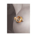 Close-up of a gold magnetic nipple clamp with a clear jewel detail on skin.