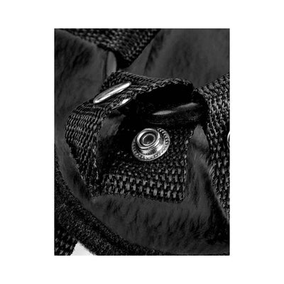 Close-up of black woven nylon strap with metal snap button and O-ring attachment on plush harness fabric.