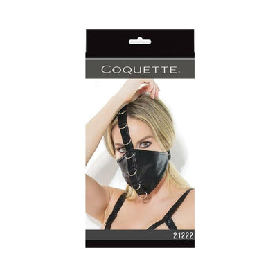 Black fetish mask with metal D-ring accents and adjustable straps, worn by a model with blonde hair.