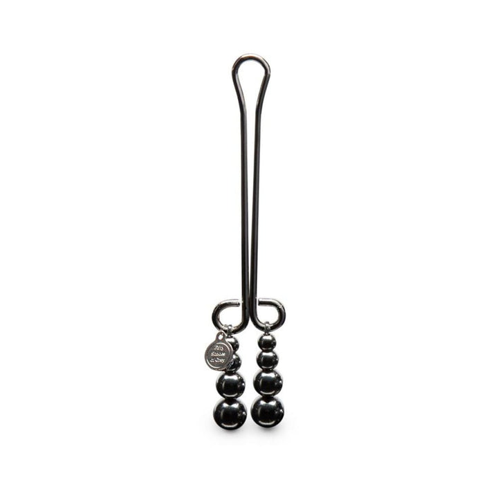 Fifty Shades Darker beaded clitoral clamp in polished black metal with hanging beads and engraved charm detail.