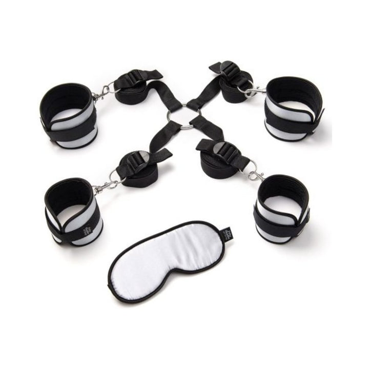 Fifty Shades of Grey Hard Limits bed restraint kit with adjustable black and white cuffs and matching blindfold on white background.