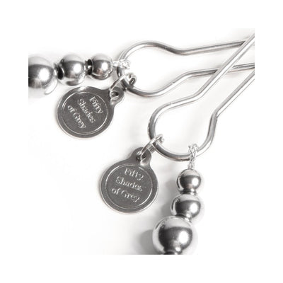 Close-up of silver Fifty Shades of Grey branded nipple clamps with adjustable screw and beaded detail on white background.