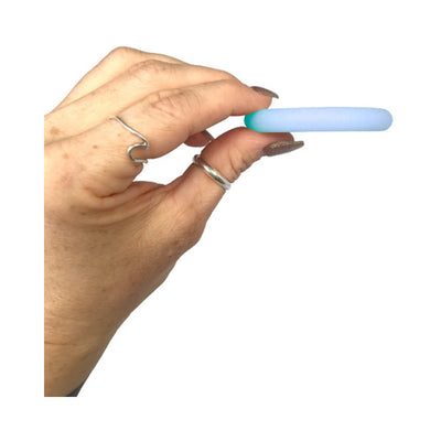 Hand holding a small, soft blue glow-in-the-dark silicone ring against a white background.