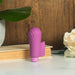 Purple Blush Gaia Eco Delight vibrator standing on a white surface with a book, green leaf, and white flower background.