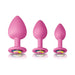 Three pink silicone spade-shaped trainer plugs in small, medium, and large sizes with colorful jewel bases.